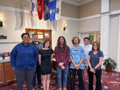 Seven students standing in front of the Azealia Trace Library for on-site veteran interviews.