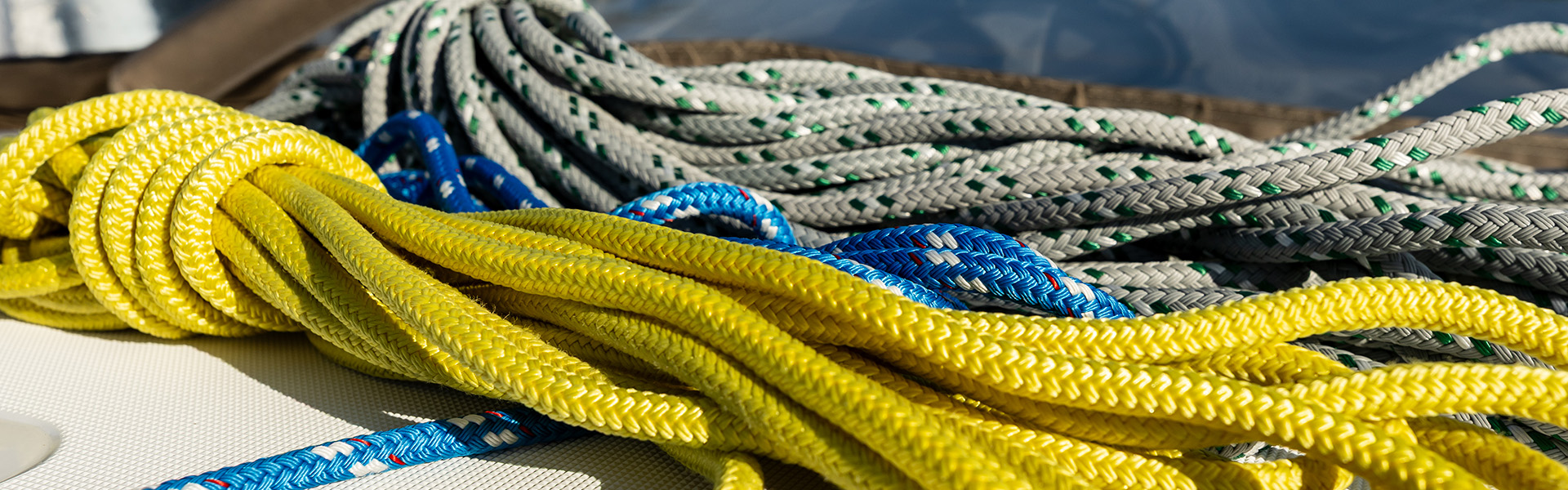Coiled yellow, blue, and white-and-green braided ropes on a boat deck.