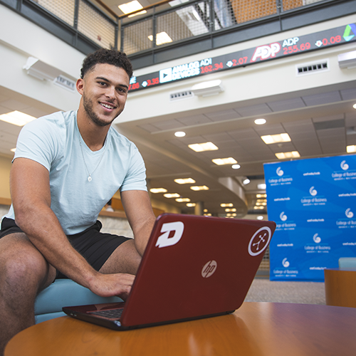 Student stands in the College of Business atrium