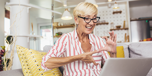 Happy senior learning sign language with laptop