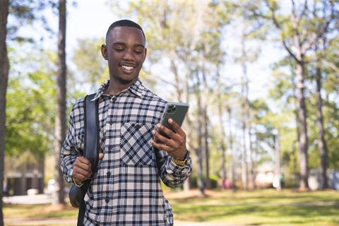 Student using a smartphone while standing outdoors.