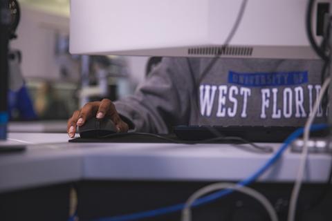Student using a mouse and keyboard while sitting in front of a computer monitor.